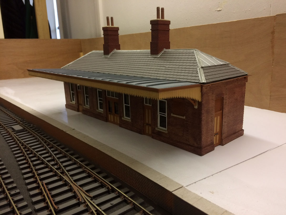 "Built for the Mere & District's new O gauge layout "Mere Abbas". The signal box has Scalelink gutters and finials plus York Model's tiles added. The station building has been modified to a hipped roof and replacement chimney stacks have been scratch built. Tiles and gutters are as the signal box. The station awning has "lead rolls" added to create more detail."
